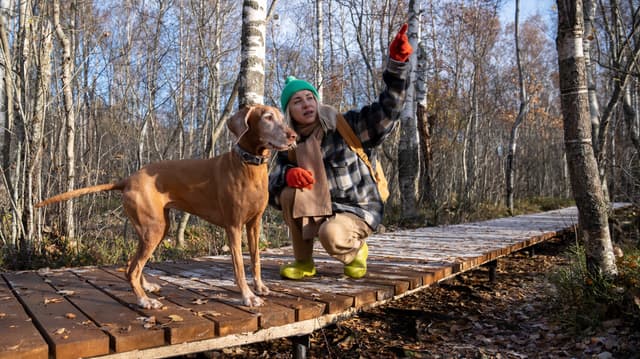 Nainen koiran kanssa luonnossa