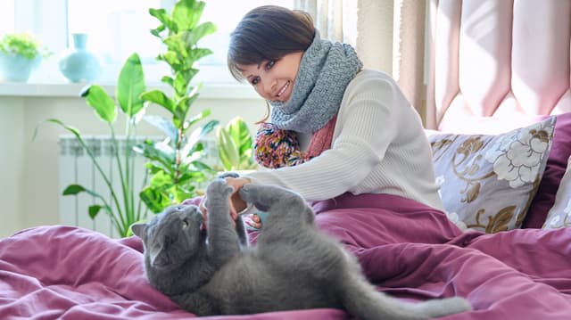 Nainen sängyllä lemmikin kanssa